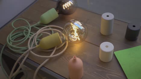 Glowing-light-bulbs-and-shades-and-coloring-wires-or-cables-on-the-table