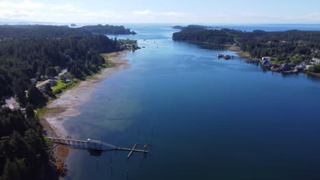 Ucluelet-British-Columbia-harbour,-a-drone-flies-over-the-bay-water-showing-Ucluelet-in-the-background