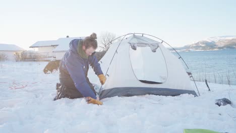 Camper-Assembling-Camping-Tent-On-Snowy-Ground-By-The-River
