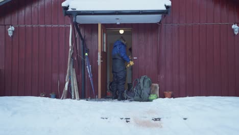 Mann-öffnet-Die-Waldtür-Der-Kabine-Und-Legt-Alaskan-Malamute-An-Die-Leine