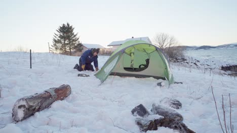 Camper-Putting-Stake-On-Corner-Of-Camping-Tent-At-Winter