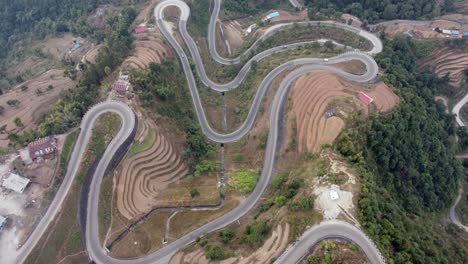 Straight-down-aerial-view-of-traffic-on-the-BP-Highway,-Bardibas-Highway,-showing-the-switchbacks-and-turns-as-it-winds-through-the-hills-of-Nepal