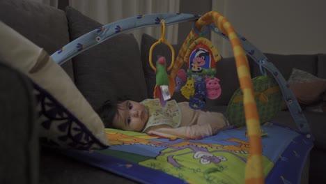 Beautiful,-cute-little-baby-lying-on-her-play-mat-with-baby-activity-gym,-being-happy-and-looking-at-the-room-around-her