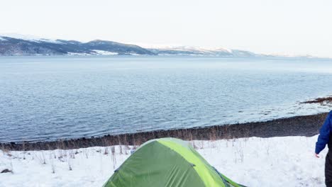 Hombre-Y-Perro-Acampando-En-Una-Colina-Cubierta-De-Nieve-Con-Una-Vista-Deslumbrante-Del-Fiordo-De-Trondheim-En-Indre-Fosen,-Trondelag,-Noruega