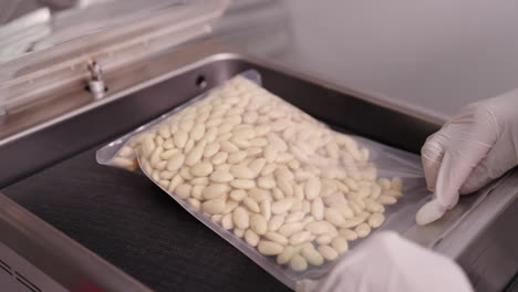Food-Production-and-Packaging,-Putting-a-Plastic-Bag-Full-of-Blanched-Almonds-in-a-Vacuum-Packing-Machine