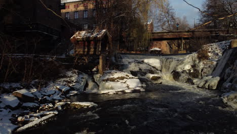 Tracking-Shot-of-Akerselva-River-in-Oslo,-Norway-during-Winter-with-Bridge