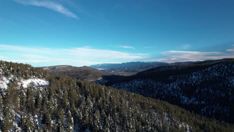 Aerial-drone-shot-of-a-dense-forested-valley-with-mountains