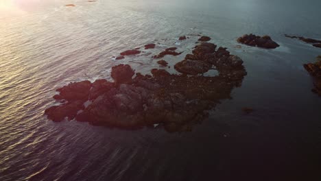 Sonnenuntergang-über-Einer-Wunderschönen-Meeresszenerie-Mit-Felsen-Und-Wellen,-Die-Im-Licht-Schimmern