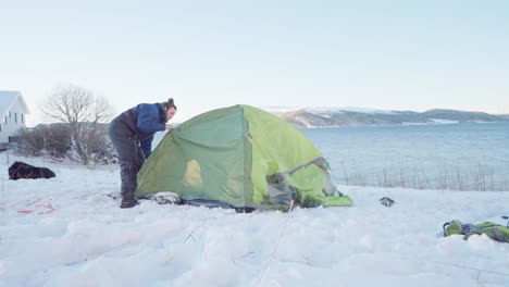 Man-Assembling-Camping-Tent-With-Ocean-Views-At-Wintertime