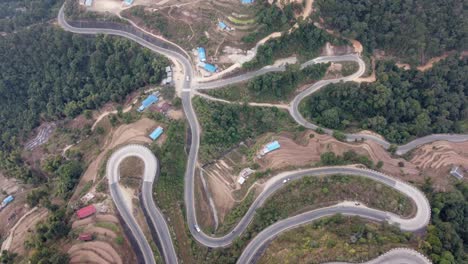 Straight-down-aerial-view-of-traffic-on-the-BP-Highway,-Bardibas-Highway,-showing-the-switchbacks-and-turns-as-it-winds-through-the-hills-of-Nepal