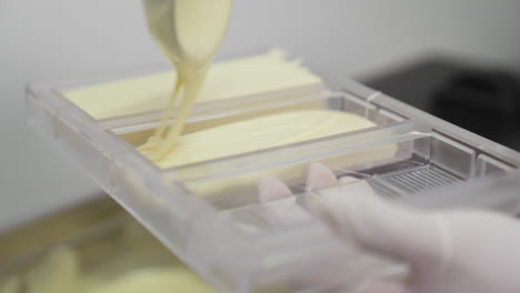 Making-White-Chocolate-Bar,-Pouring-White-Chocolate-into-Plastic-Mold-with-a-Ladle-in-Confectionary