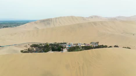 Person-on-Sand-Dunes-overlooking-Huacachina-Desert-Oasis-in-Peru,-Aerial