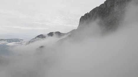 Felsige-Bergkette,-Die-über-Dichter-Wolkenlandschaft-Steht,-Drohnenansicht-Aus-Der-Luft,-Während-Sie-Durch-Wolken-Fliegt