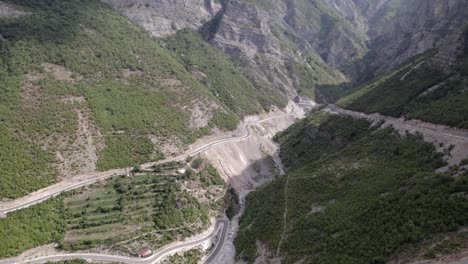 Bird's-Eye-Front-Plane-Drone-Video-over-the-"Rrapsh-Serpentine"-mountain-pass-on-the-Sh20-road-in-Grabom,-Albania,-Leqet-e-Hotit