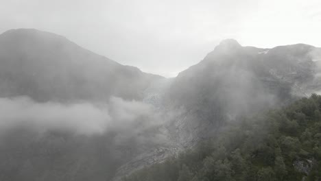 Flying-through-dense-fog-and-reveal-majestic-glacier,-high-altitude-drone-view
