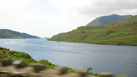 Driving-through-the-Ireland-countryside-with-beautiful-green-Lakes,-Mountains-and-hills