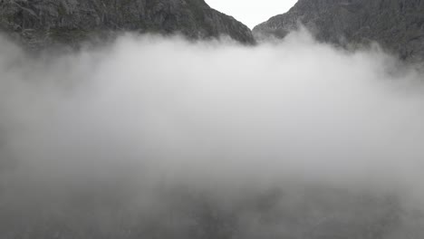 Cordillera-Alta-Que-Se-Alza-Sobre-Un-Paisaje-Nuboso-Esponjoso,-Toma-Aérea-De-Drones