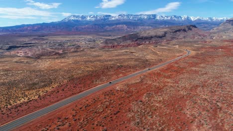 Drone-Aéreo-Disparado-En-El-Desierto-Con-Una-Carretera-Transitada-Y-Montañas