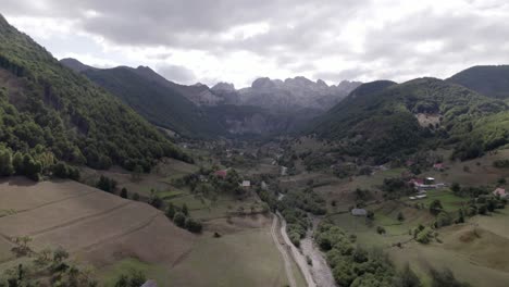 Video-Drone-Del-Avion-Frontal-Avanzando-Sobre-El-Valle-De-Lepushë-Sobre-El-Rio-Lëpusha,-El-Sh20-En-Albania,-Se-Pueden-Ver-Casitas-Del-Pueblo,-Un-Cielo-Algo-Nublado-Y-El-Rio-Seco
