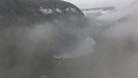 Pure-mountain-lake-while-flying-through-fluffy-cloudscape