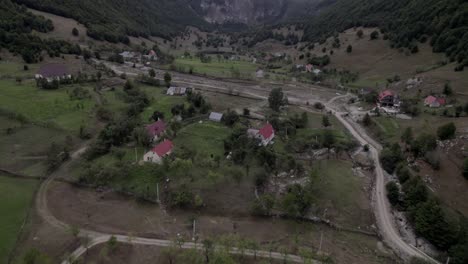 Video-with-descriptive-panning-Drone-advancing-over-the-Lepushë-valley-above-the-Lëpusha-river,-the-sh20-in-Albania,-you-can-see-small-houses-of-the-town,-somewhat-cloudy-sky-and-the-dry-river
