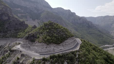 Drone-video-of-empty-description-plane-over-the-"Rrapsh-Serpentine"-mountain-pass-on-the-Sh20-road-in-Grabom-Albania,-you-can-see-a-motorcycle-and-car-passing-by