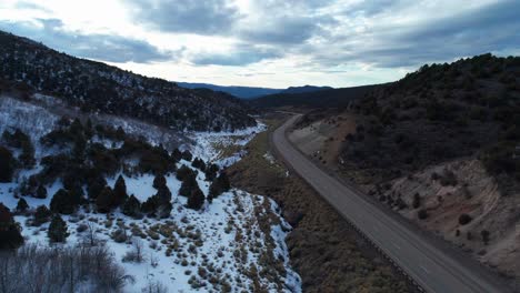 Aerial-drone-shot-of-a-calm-highway-that-bends-in-between-two-mountains