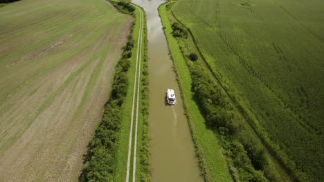 Aerial-shot-of-a-small-vessel-in-the-canal-in-the-middle-of-the-farm-fields