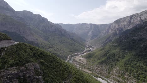 Drone-video-of-side-shot-"slider"-discovery-over-a-peak-of-the-"Rrapsh-Serpentine"-mountain-pass-on-the-Sh20-road-in-Grabom-in-Albania,-Leqet-e-Hotit