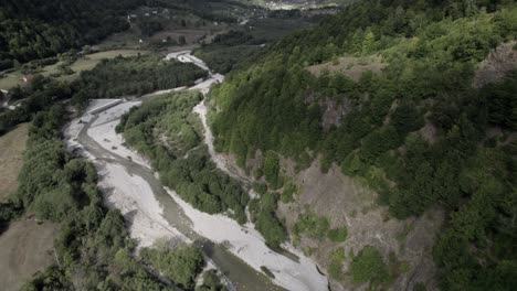 Descriptive-panning-Drone-video-advancing-over-the-Vermosh-valley-above-the-Vermoshi-river,-the-sh20-at-the-height-of-Bashkimi,-Albania