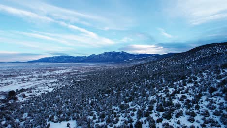 Aerial-drone-shot-moving-over-the-snowy-desert-with-a-mountain-range