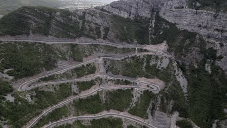 Drone-video-of-a-revealing-bird's-eye-view-of-the-"Rrapsh-Serpentine"-mountain-pass-on-the-Sh20-road-in-Grabom,-Albania,-Leqet-and-Hotit-can-be-seen-circulating-vehicles