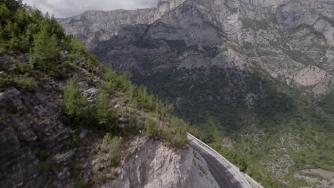 Drone-video-of-ascending-frontal-discovery-plane-over-the-mountain-pass-"Rrapsh-Serpentine"-on-the-Sh20-road-in-Grabom,-Albania,-ends-in-front-of-the-mountain-Leqet-e-Hotit