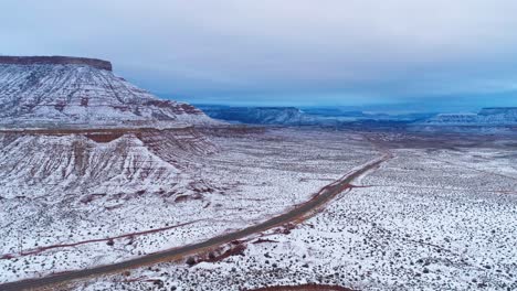 Aerial-drone-shot-high-above-a-highway-in-the-desert-covered-in-snow