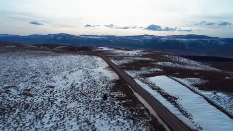 Drone-shot-of-a-long-and-straight-highway-on-top-of-a-mountain-with-snow