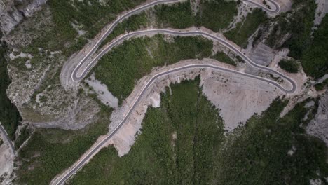 Drone-video-of-previous-revealing-plane-from-a-bird's-eye-view-over-the-"Rrapsh-Serpentine"-mountain-pass-on-the-Sh20-road-in-Grabom,-Albania,-Leqet-and-Hotit-can-be-seen-circulating-vehicles