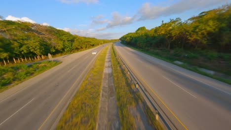 Cars-Driving-Through-Autovia-del-Este,-Dual-Carriageway-At-Dusk-Between-Woodlands-In-Dominican-Republic