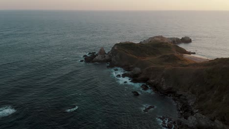 Aerial-orbit-shot-of-famous-Cerro-Sagrado-View-Point-at-Shoreline-with-Pacific-Ocean-in-backdrop-during-sunset-in-Mexico
