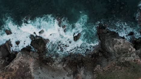 Landing-top-down-shot-of-crashing-waves-against-vast-rocky-coastline-with-Comet-Point-in-Mexico