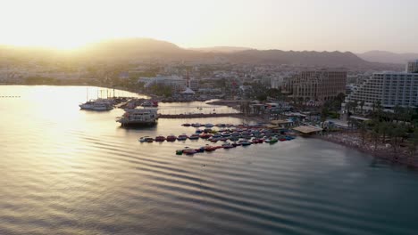 Luftaufnahme-Des-Sonnenuntergangs-über-Booten-Und-Luxushotels-An-Der-Küste-Von-Eilat,-Israel