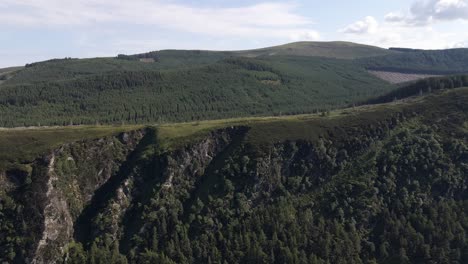 Drone-shot-of-a-cliff-face-with-a-forest-on-top-of-it