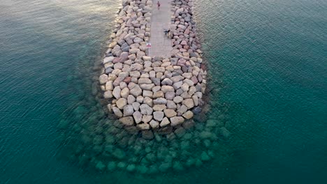 Aerial-footage-revealing-scene-from-a-breakwater-at-the-Red-Sea-to-sunset-over-Eilat-city-in-South-Israel