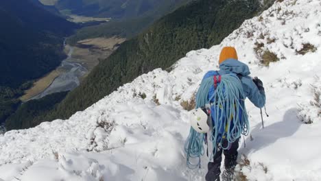 Hombre-Escalando-Montañas-Caminando-Por-La-Nieve-Sobre-Un-Hermoso-Valle-En-Un-Día-Soleado,-Tiro-De-Mano