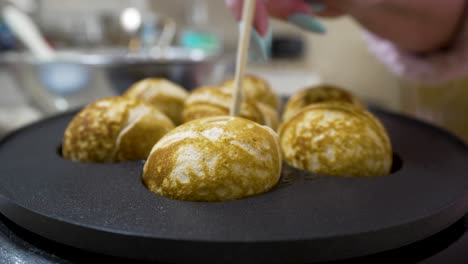 Turning-aebleskivers-in-the-pan-to-cook-them-evenly-in-the-rounded-pockets---AEBLESKIVER-SERIES