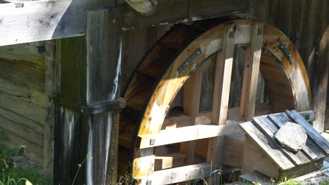 Close-up-shot-of-old-wooden-water-mill-rotating-in-mountains-of-Switzerland-during-sun---A-watermill-or-water-mill-is-a-mill-that-uses-hydropower