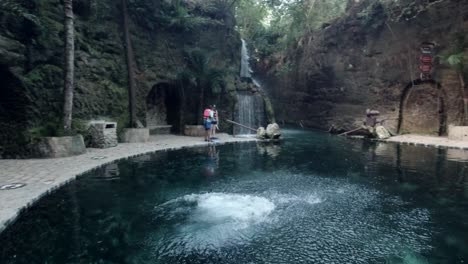 Hispanischer-Mann,-Der-In-Einen-Natürlichen-Pool-Mit-Wald-Im-Hintergrund-Springt