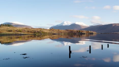 Aerial-drone-footage-flying-close-over-gentle-ripples-in-the-water-of-Loch-Etive-in-Glen-Etive-in-the-Highlands-of-Scotland-with-snow-capped-mountains-in-the-background-and-beautiful-reflective-water