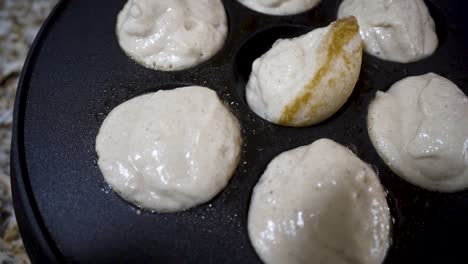 Turning-aebleskivers-in-a-cast-iron-pan-as-they-cook-in-the-oil-to-a-golden-brown---close-up-in-slow-motion-AEBLESKIVER-SERIES