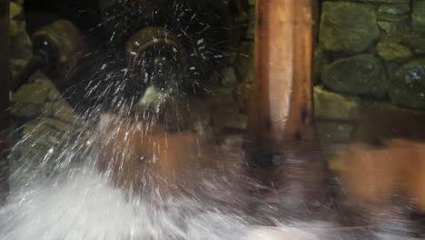 Close-up-shot-of-wooden-water-mill-spinning-and-splashing-with-water