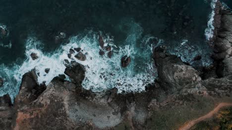Ascend-Top-aerial-drone-view-of-waves-crashing-on-rocky-coastline